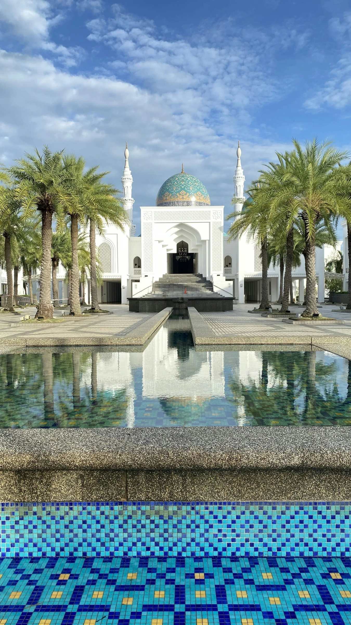 The patterned dome, white entrance, palm-lined courtyard and reflecting pool at Masjid Al-Bukhary in Alor Setar.