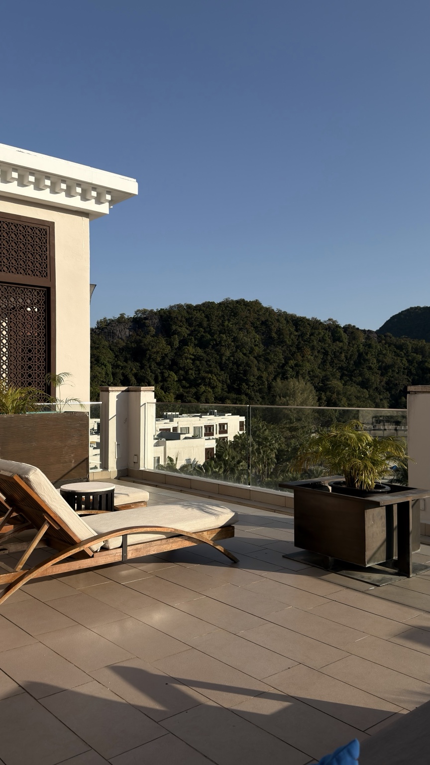 Teres hotel dengan kerusi santai dan pemandangan bukit berhutan
