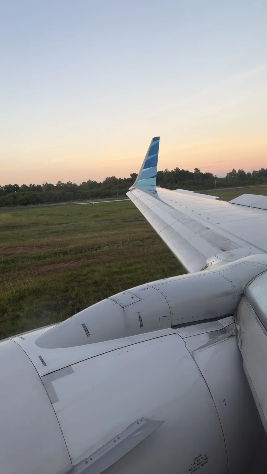 An aircraft engine and wing with a Garuda Indonesia winglet, on the ground at dusk.