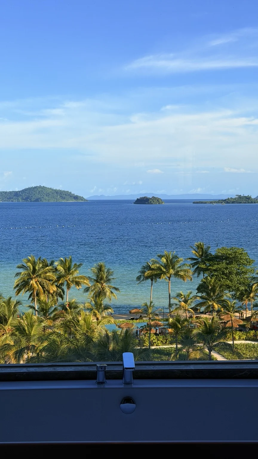 Blue water, small islands and coconut palms through a bathroom window at Lampung Marriott Resort & Spa.