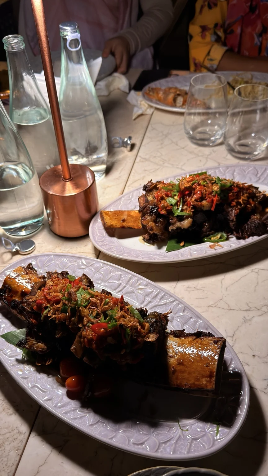 Two platters of main dishes on a restaurant table at night.