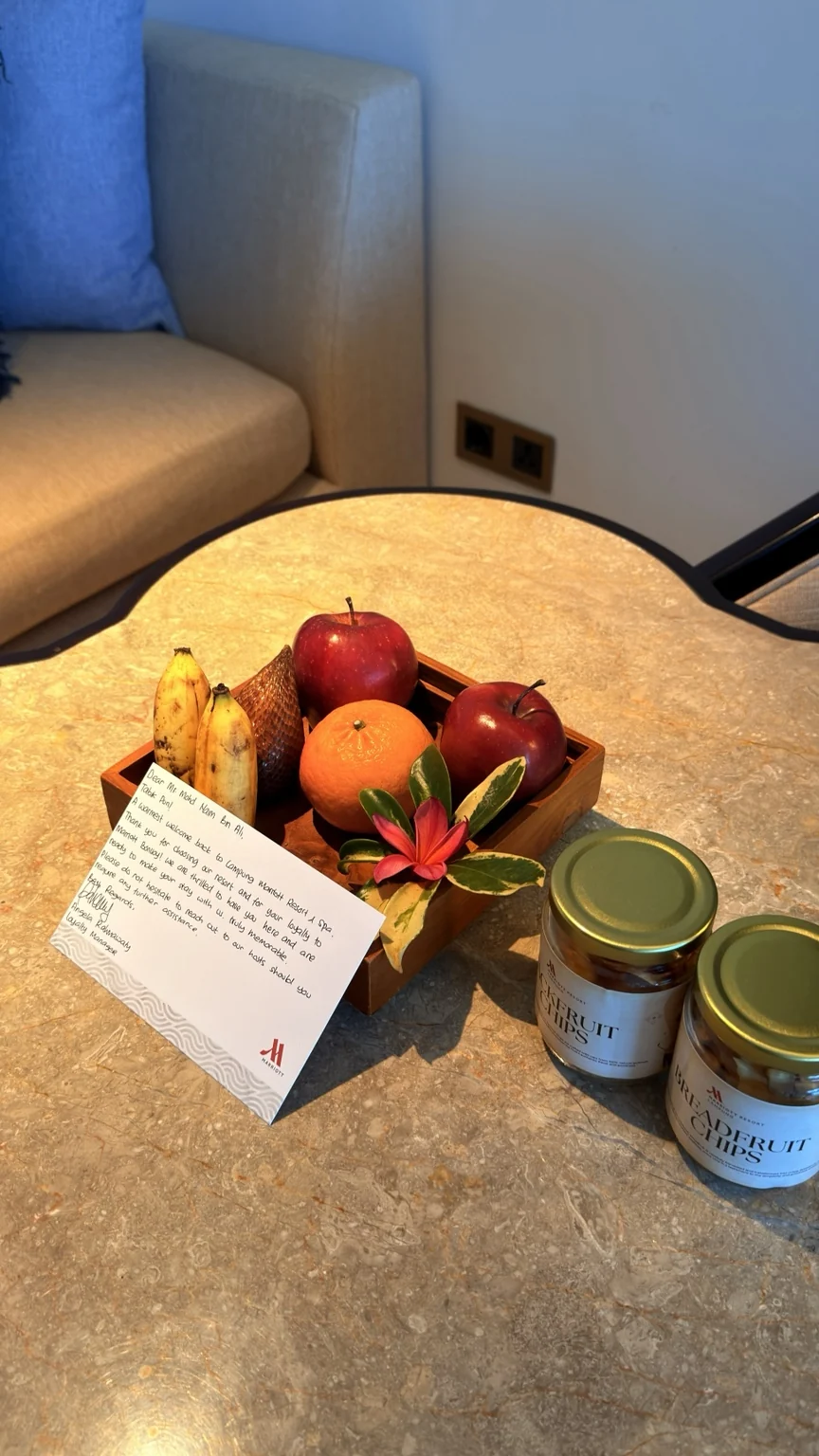 Fruit, two jars of jackfruit chips and a Marriott welcome note on a table in the room.