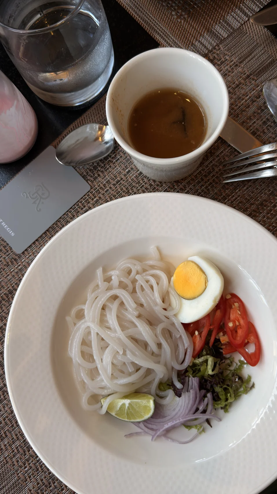 Mi laksa dengan telur dan hirisan sayur, bersama kuah yang dihidang berasingan.