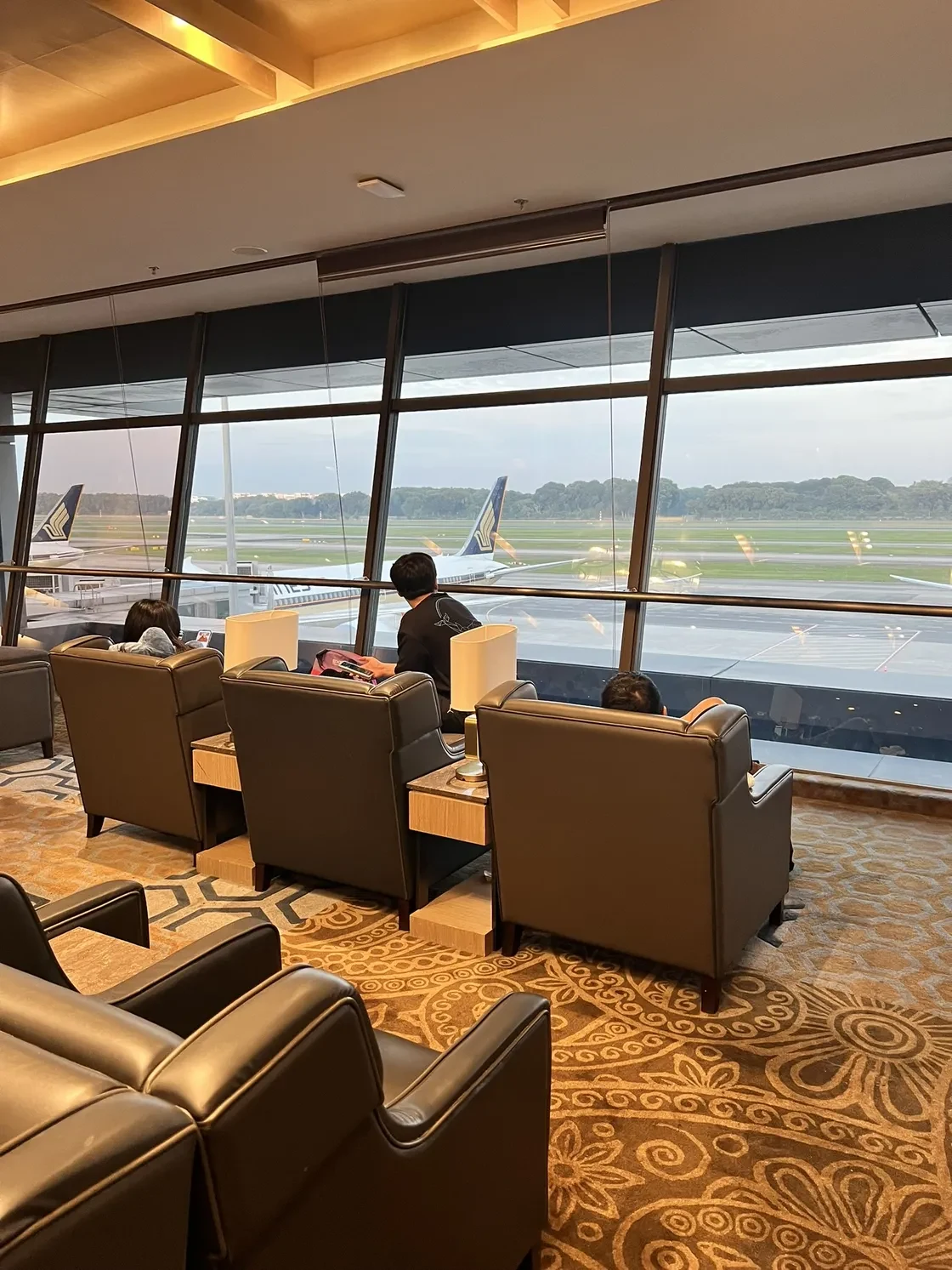 Plaza Premium lounge seats facing large windows and aircraft at Singapore Changi.
