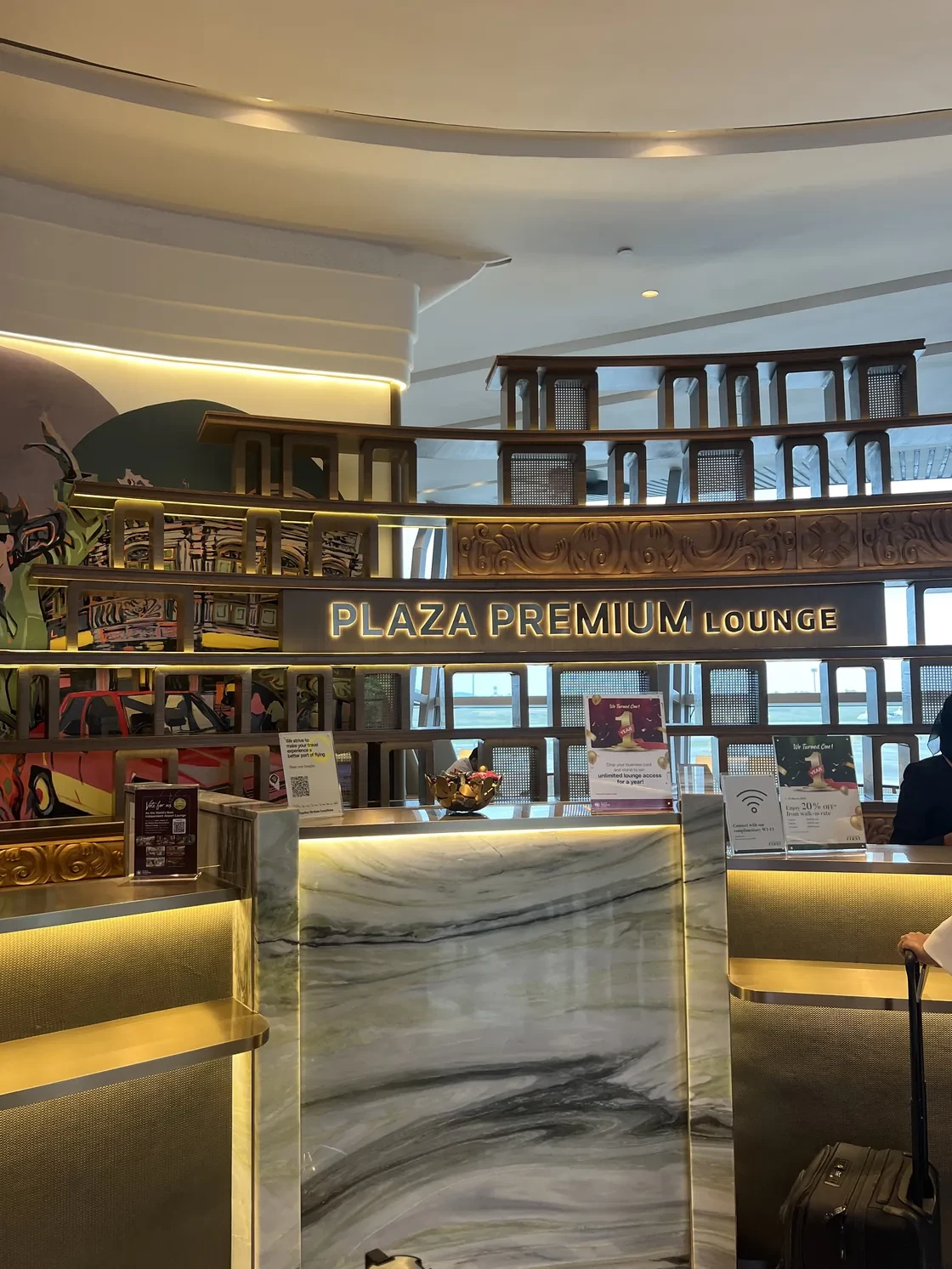 Plaza Premium Lounge entrance with seats and curved ceiling at KLIA.