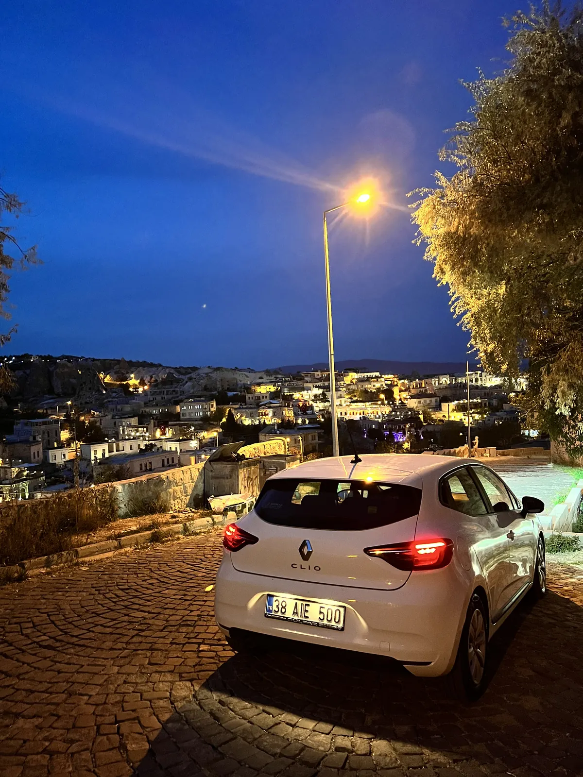 Kereta sewa putih diparkir di atas Cappadocia waktu senja
